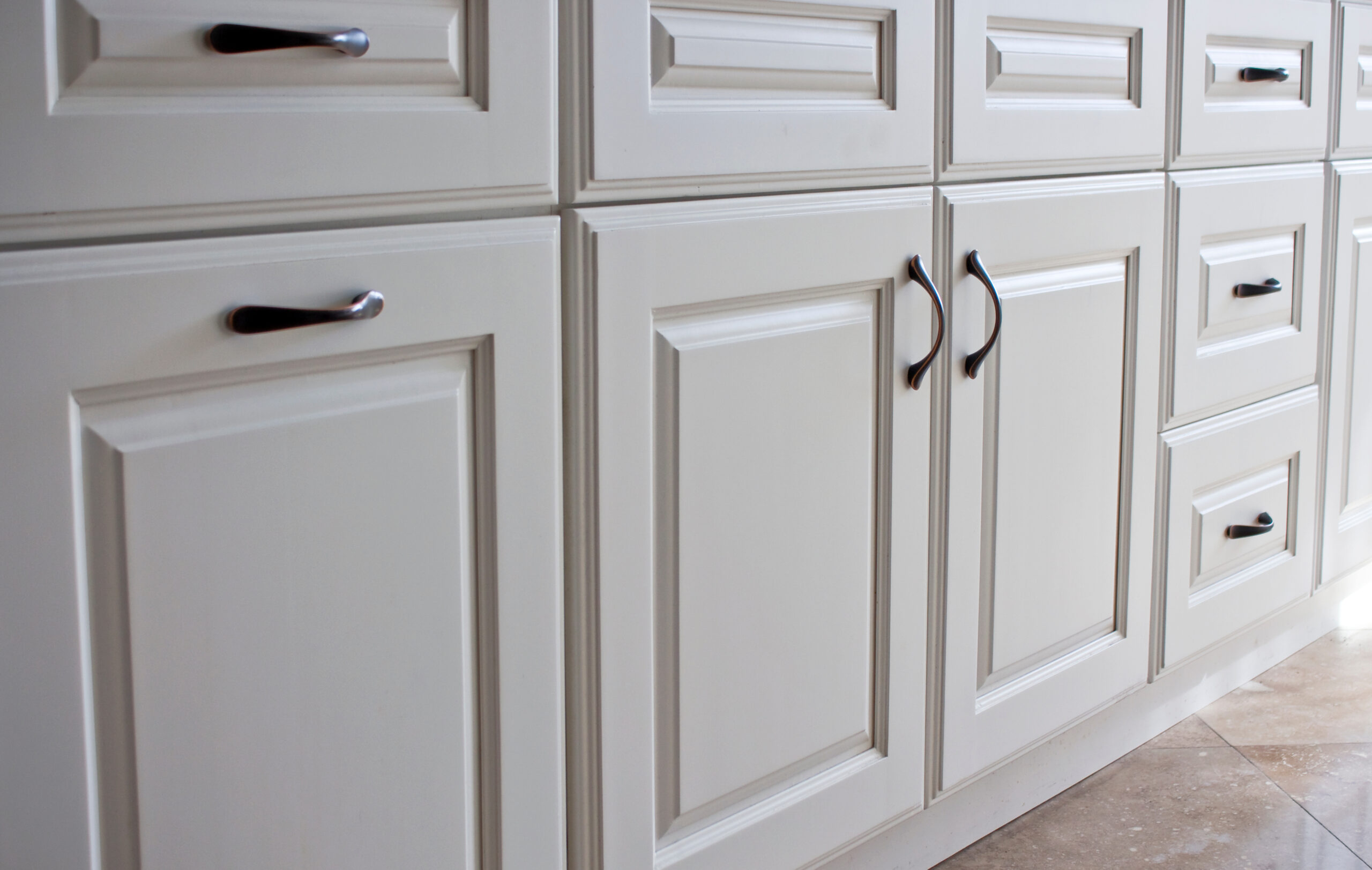 Close up of white kitchen cabinets with dark polished metal handles